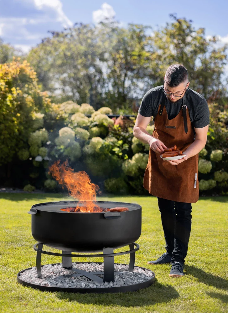 Man grilling at a COOK KING fire bowl in the garden