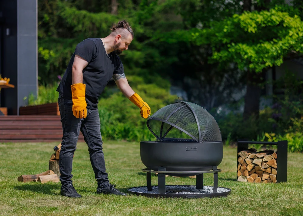 Man opening the spark screen of a COOK KING fire bowl